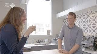 A  man and a woman in a kitchen, smiling with a cup of coffee